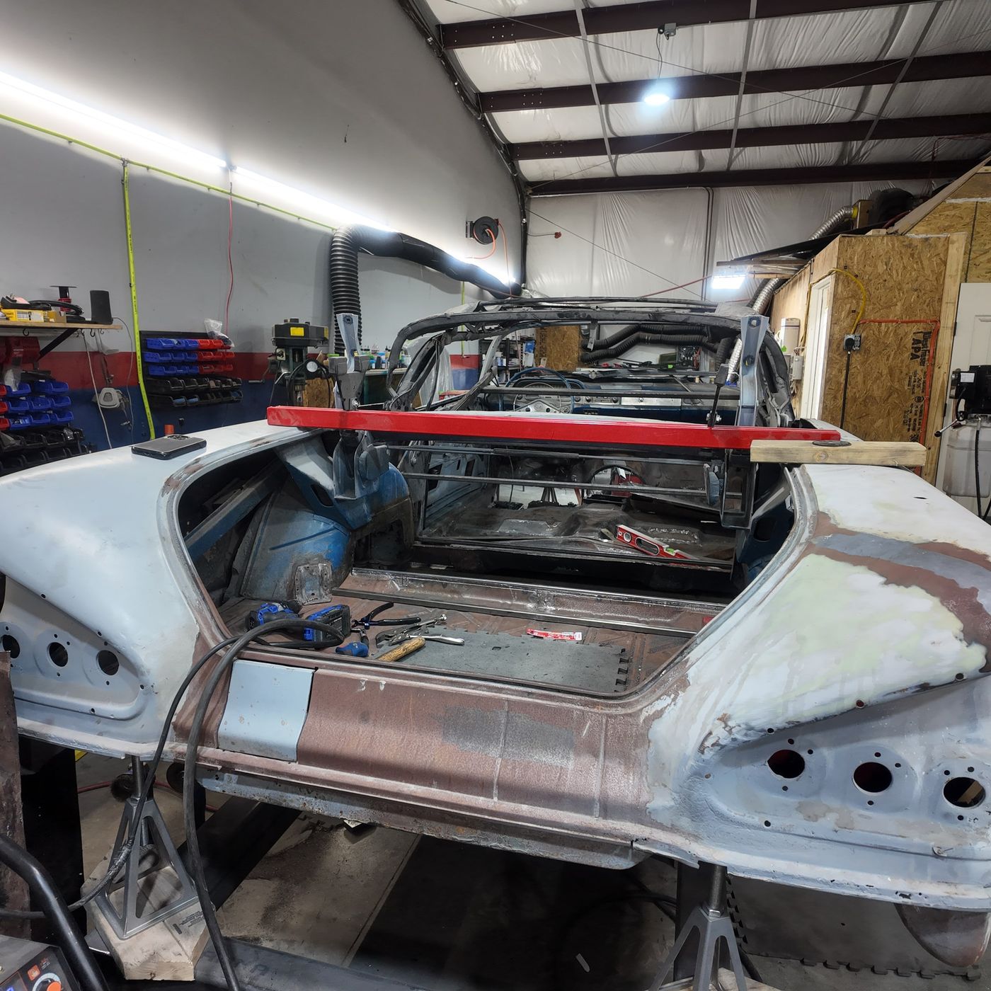 Stripped 1958 Chevrolet Impala body on a jig in the shop, rear quarter view, with the new trunk floor fitted