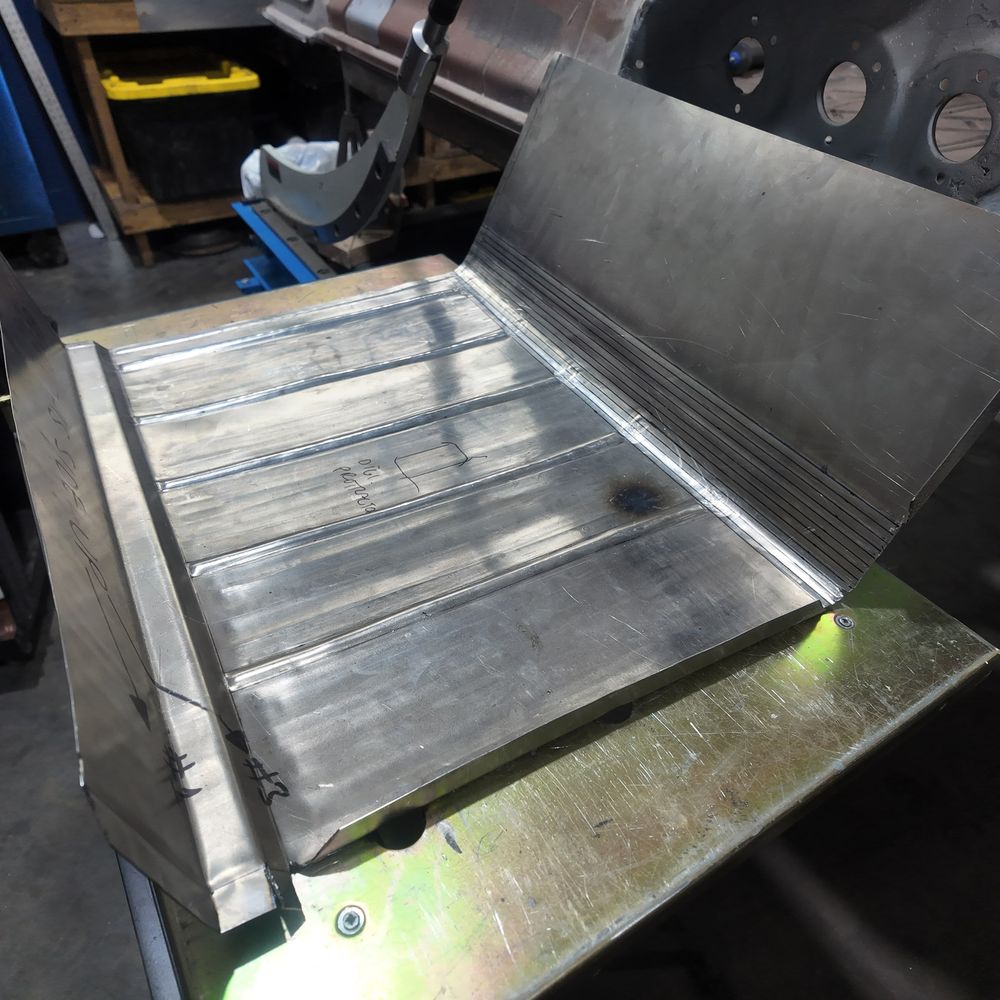 Hand-formed sheet-metal panel with pressed ribs sitting on a workbench