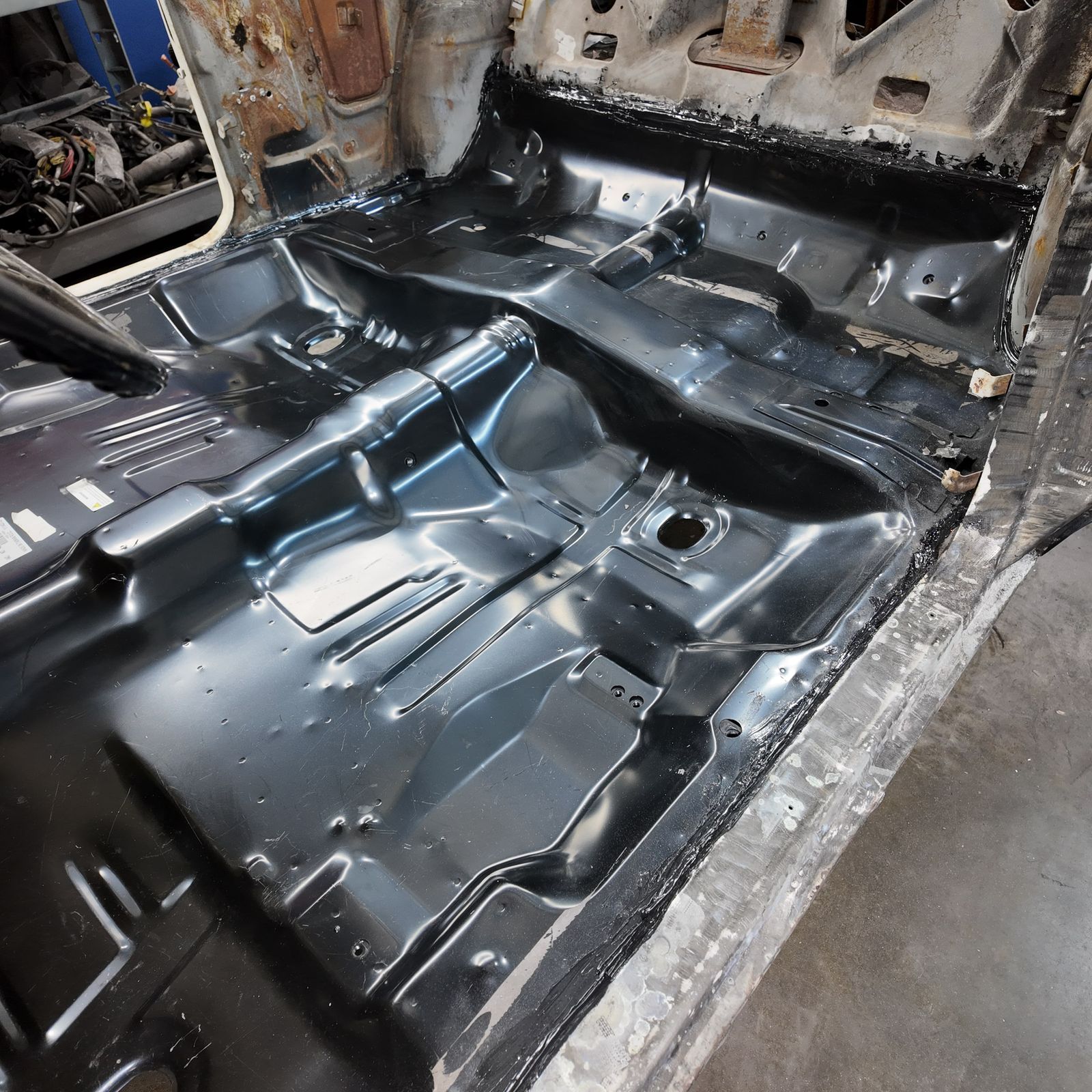 Stripped classic car body with new floor pans on the shop floor