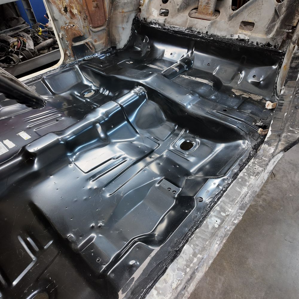 Bare interior of a classic car with brand-new black floor pans welded in