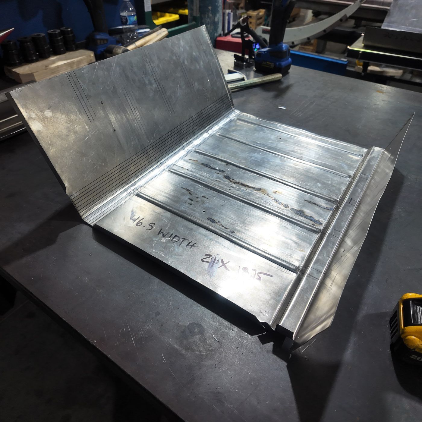 New hand-formed ribbed trunk floor pan on the workbench with dimensions marked in pen