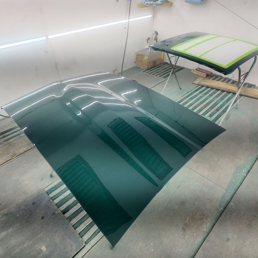 Freshly painted dark green hood curing in the paint booth under fluorescent light
